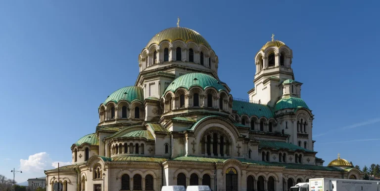 Gold and green domes of a large cathedral under a clear blue sky in Sofia