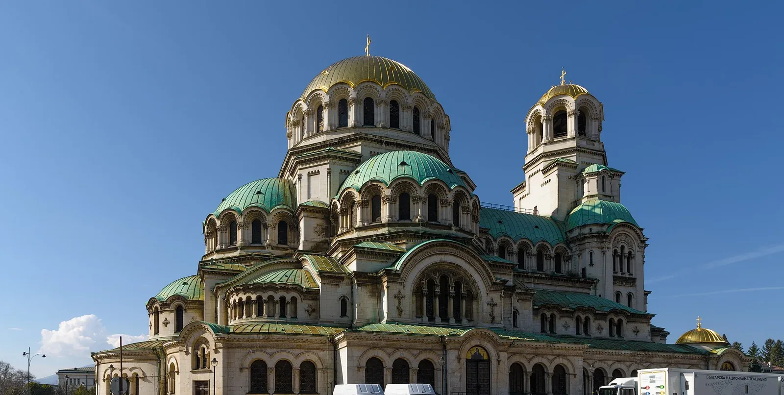 Gold and green domes of a large cathedral under a clear blue sky in Sofia